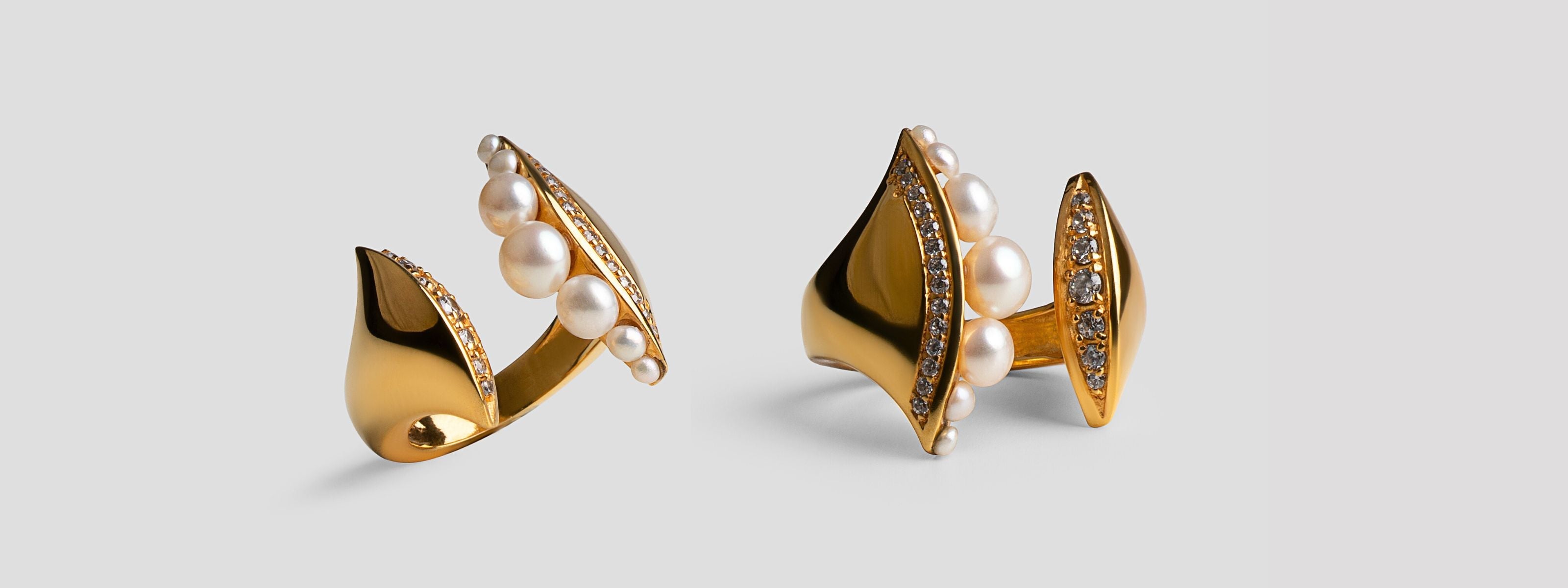 Open sculptural gold ring with graduated pearls and pavé zircons on a soft grey background, MHARI gifting edit.