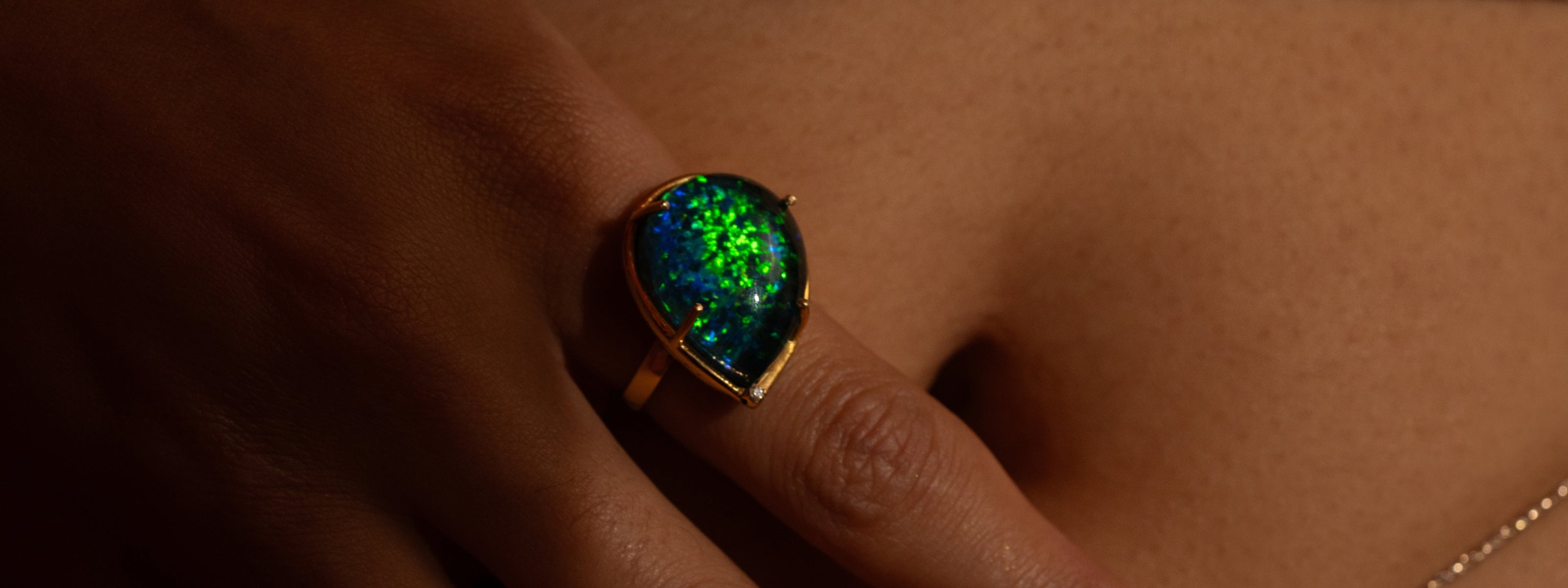 A Mhari Mastaani teardrop ring with a green-blue opal in gold-plated silver, worn on the hand