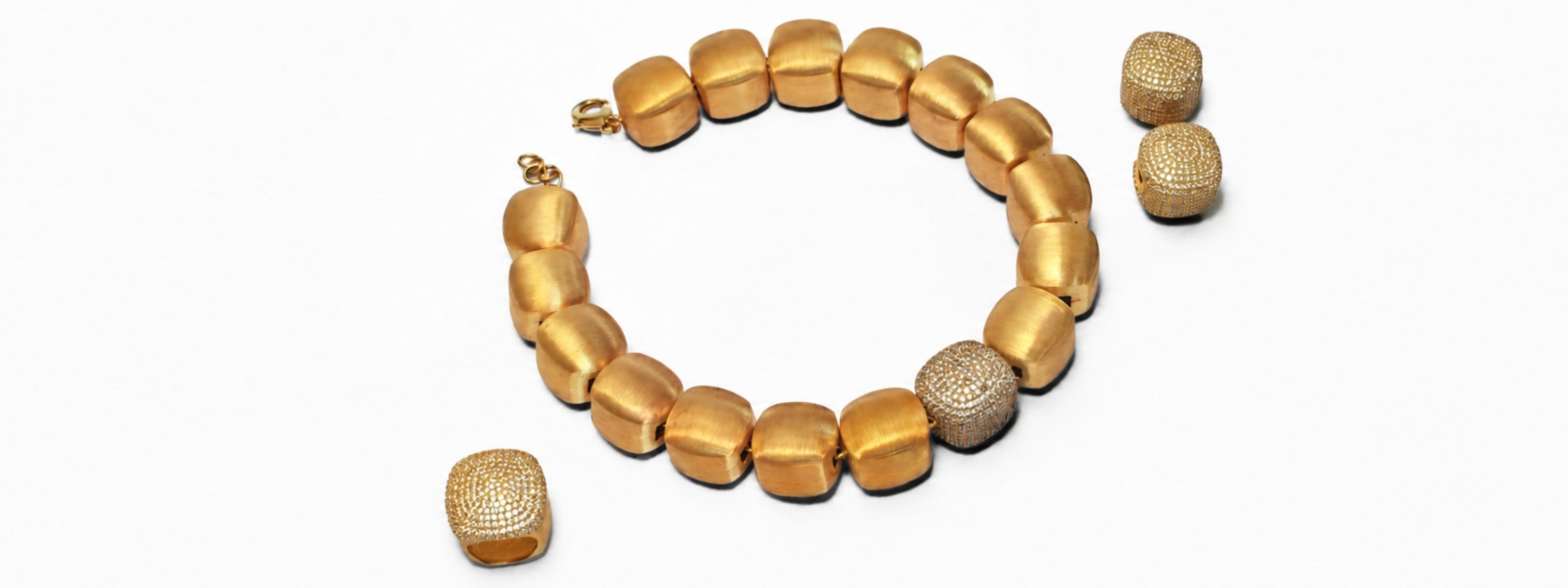 Cubic Majesty brushed gold cube necklace with CZ accent pieces arranged in a flat lay, MHARI sets collection.