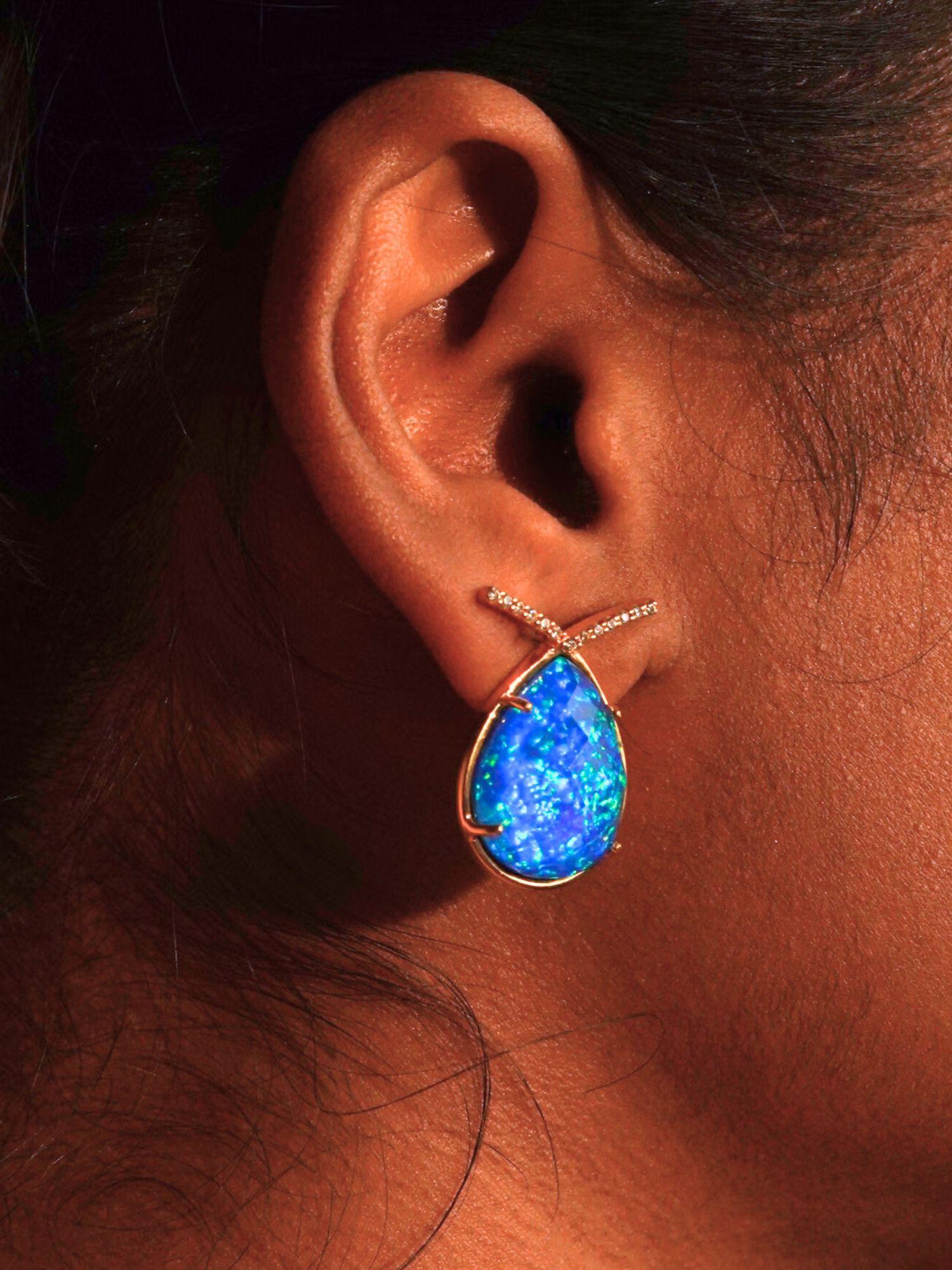 Aeris vivid blue opal teardrop statement earring worn close to ear on model in warm editorial shot.