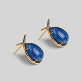 Angled product shot of Aeris deep blue teardrop earrings showing stone texture and gold setting.