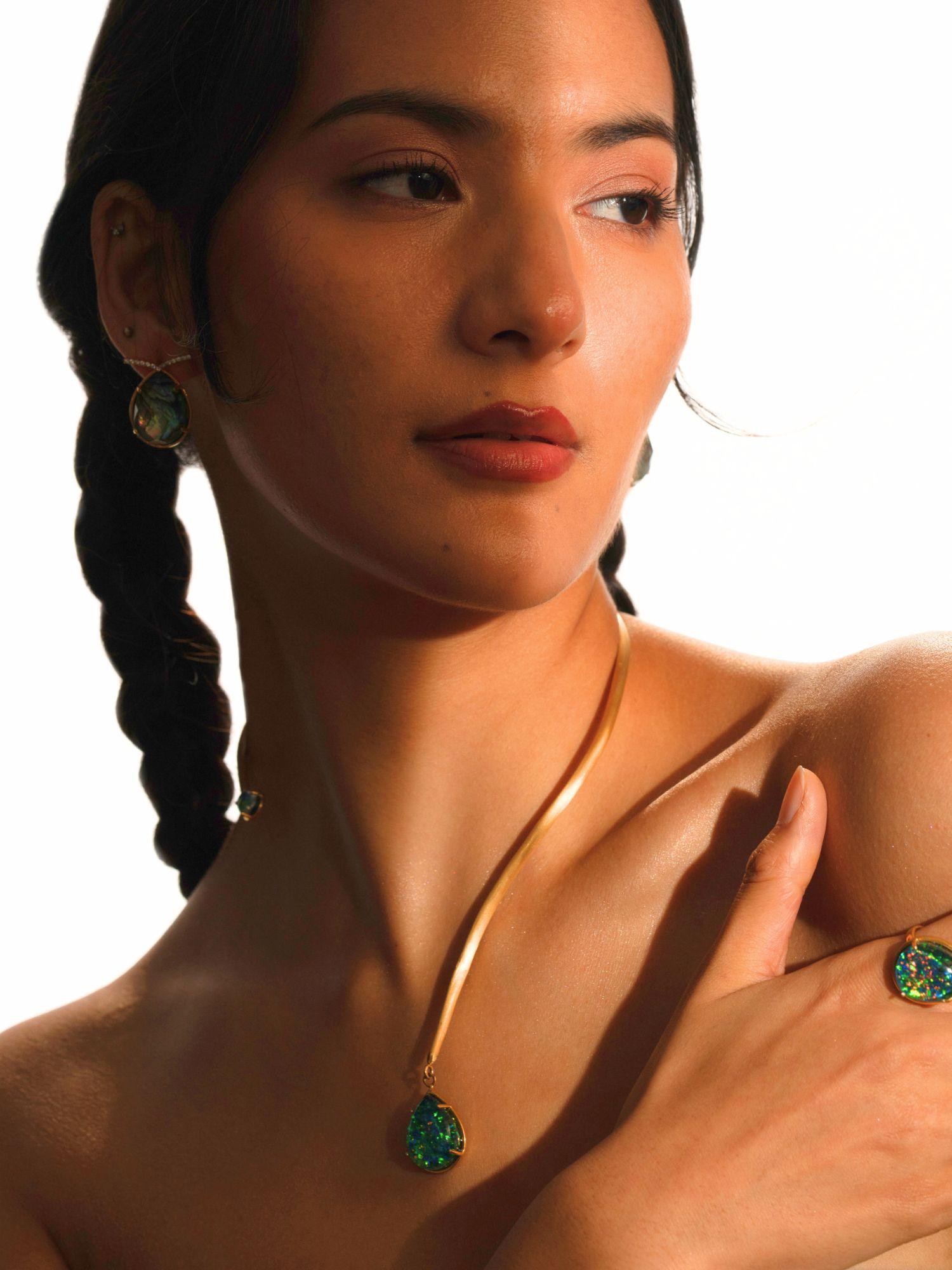Model wearing Aeris opal pendant necklace and matching earrings in a warm editorial portrait.