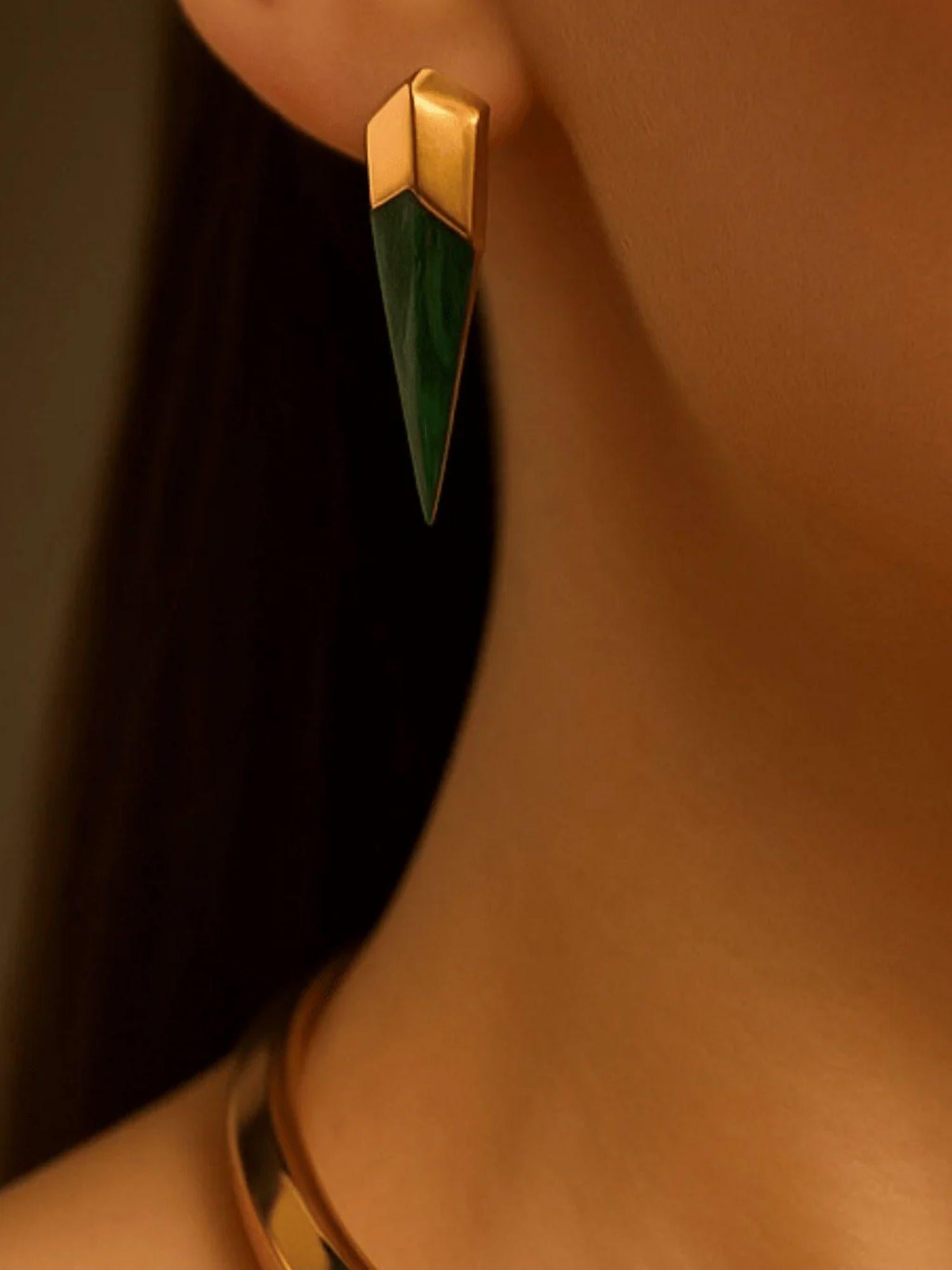 Close-up of malachite spike earring on ear with gold collar necklace visible