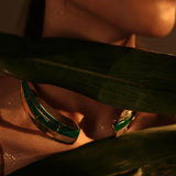 Model wearing malachite collar necklace and earrings partially obscured by tropical leaf