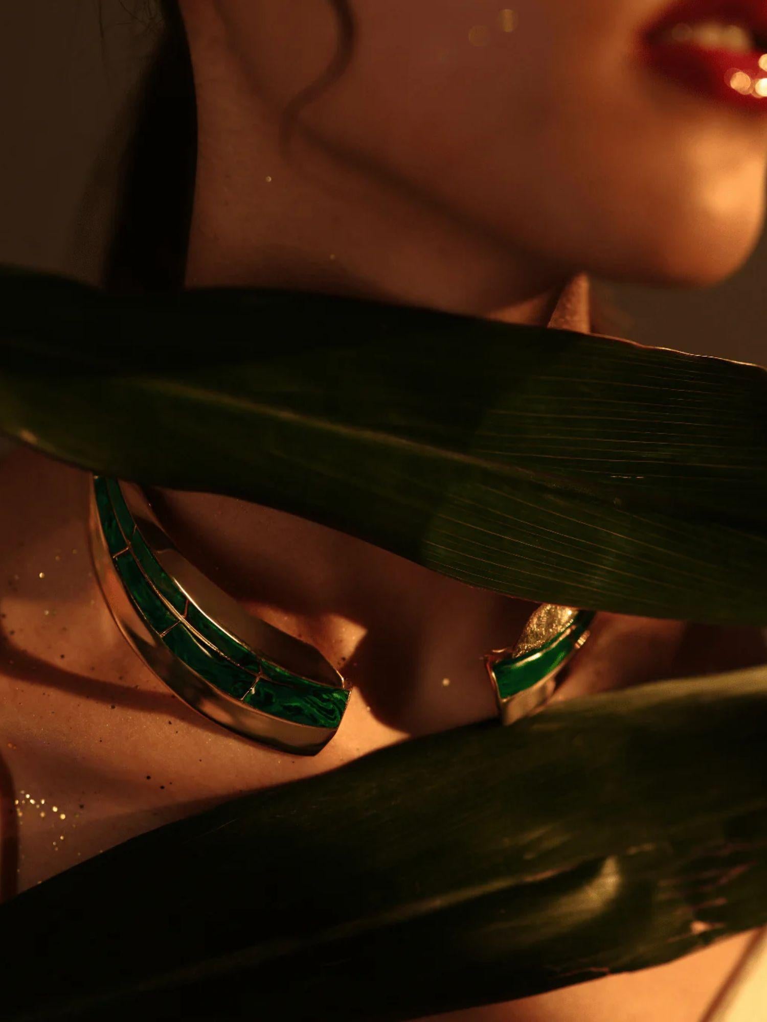 Model wearing malachite collar necklace and earrings partially obscured by tropical leaf