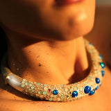 Close-up of blue opal hasli necklace on model's collarbone in warm light
