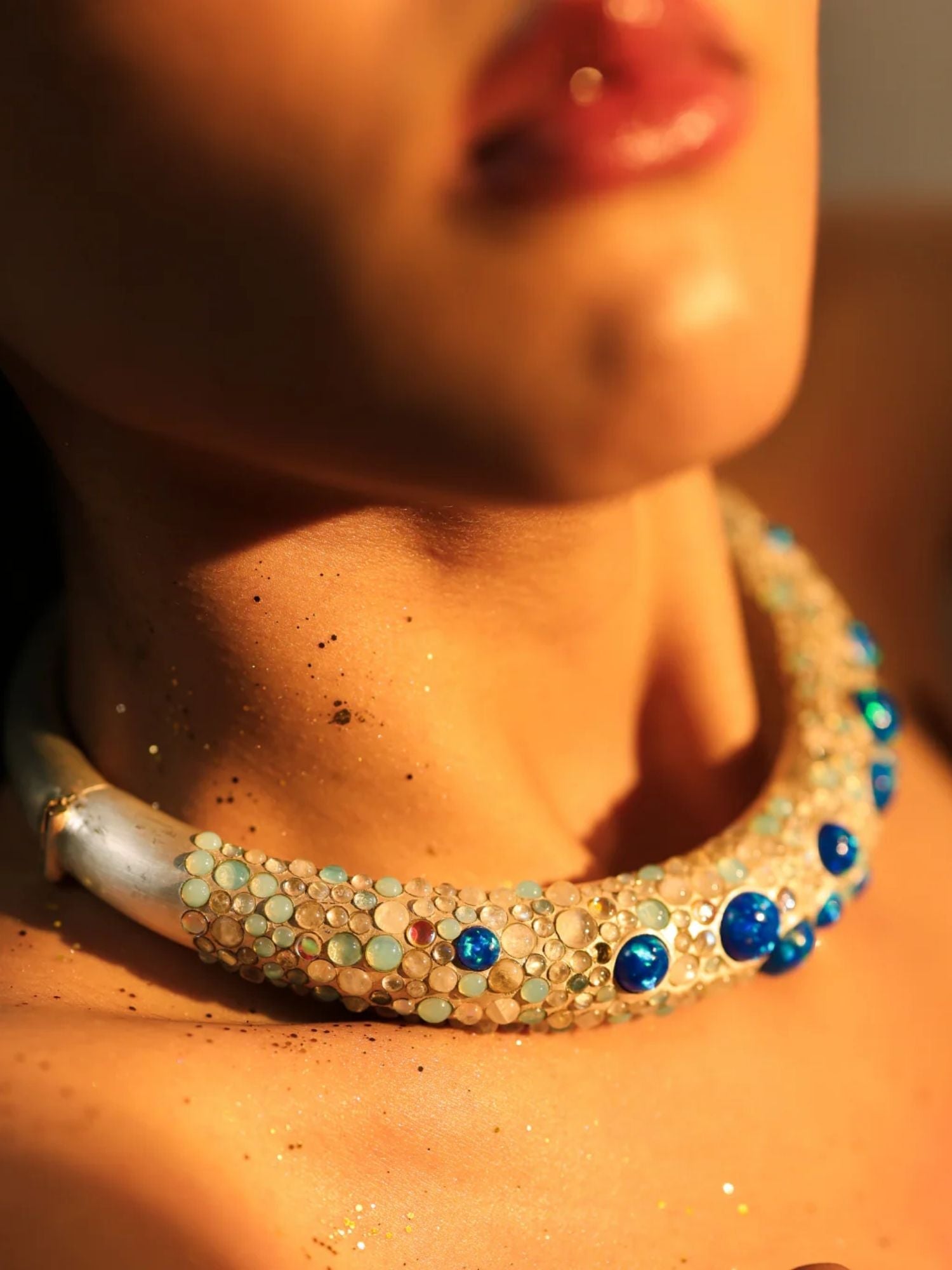 Close-up of blue opal hasli necklace on model's collarbone in warm light