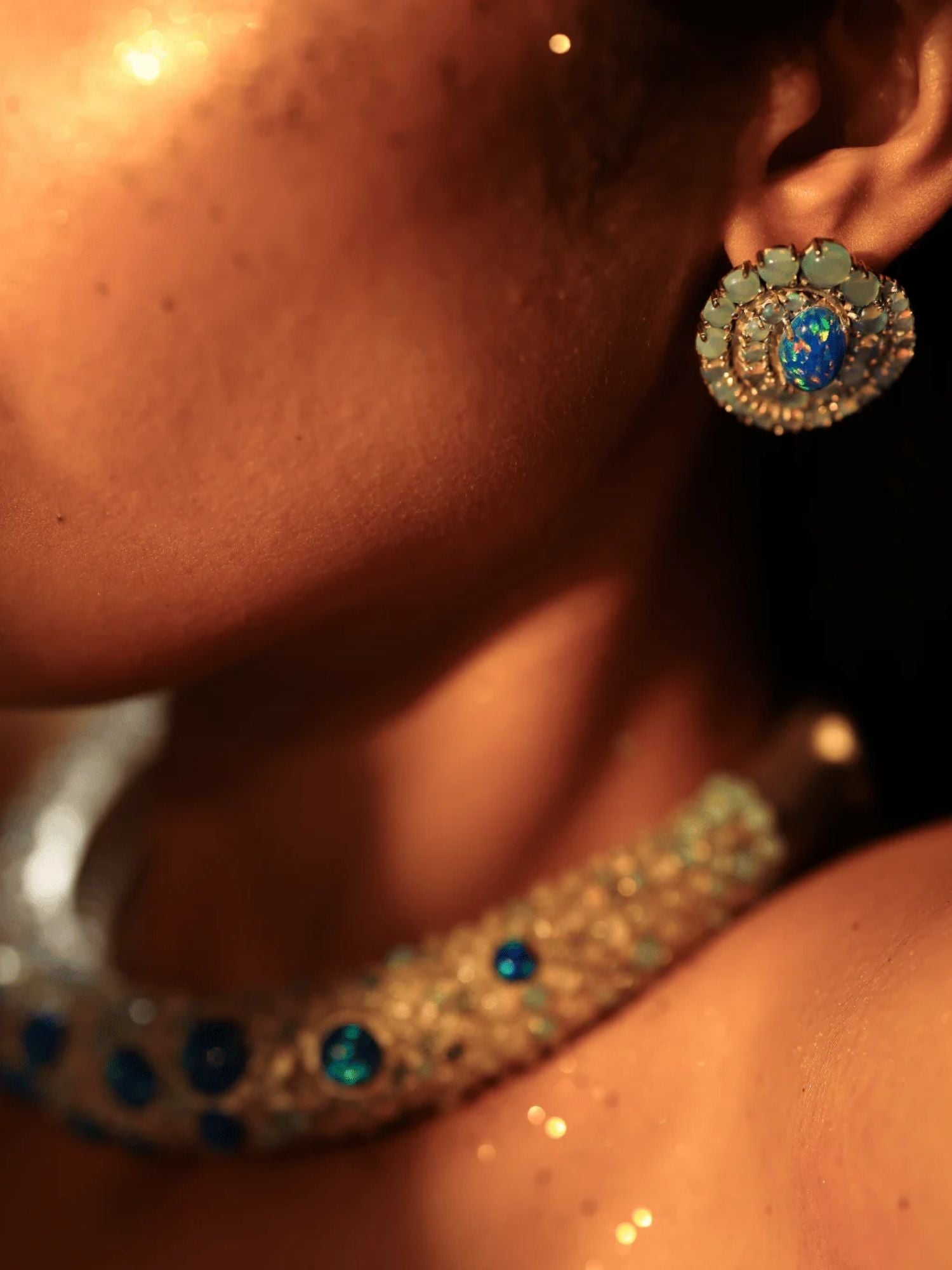 Side profile of model wearing blue opal spiral earring with hasli necklace visible