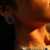 Blue opal spiral earring on model's ear with light catching stone surface