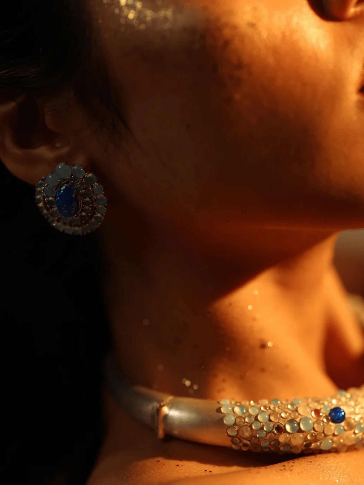 Blue opal spiral earring on model's ear with light catching stone surface