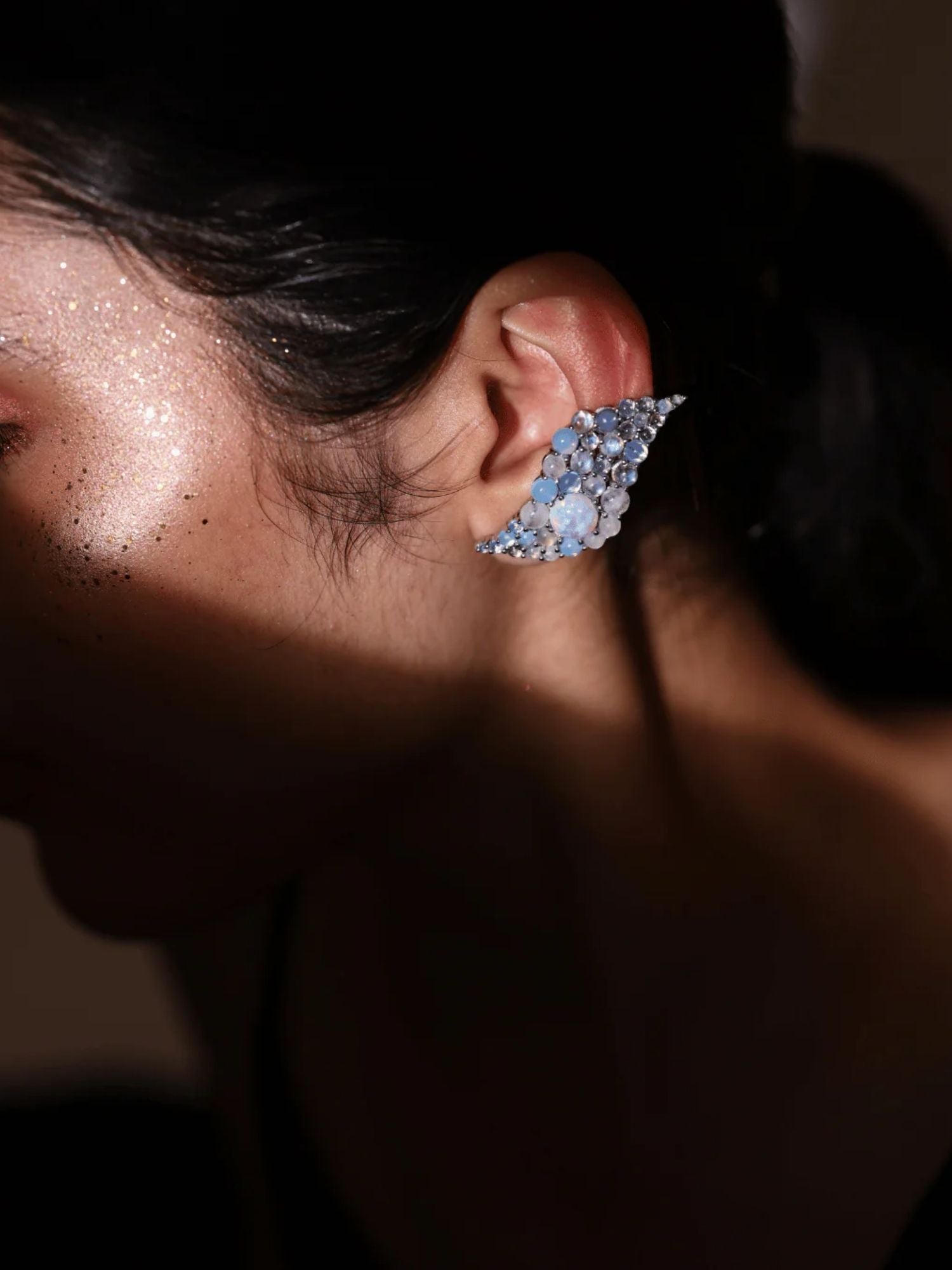 Close-up of blue opal wave ear cuff on model with light on cheekbone