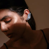 Model wearing blue opal wave ear cuff, eyes closed, warm ambient light