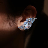 Model wearing blue opal wave ear cuff, dark close-up showing stone detail
