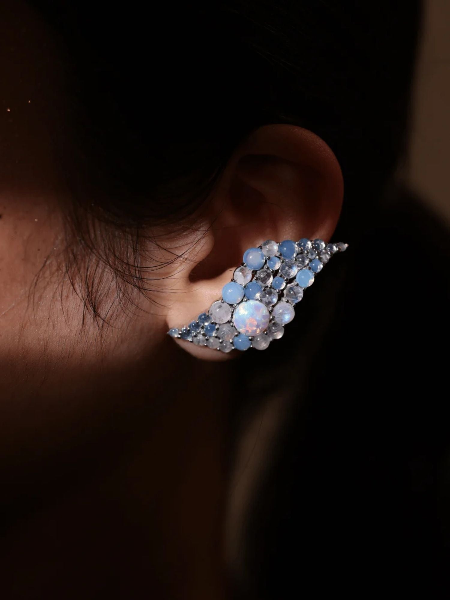 Model wearing blue opal wave ear cuff, dark close-up showing stone detail