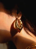 Model wearing large gold claw earring, close-up side profile in warm light