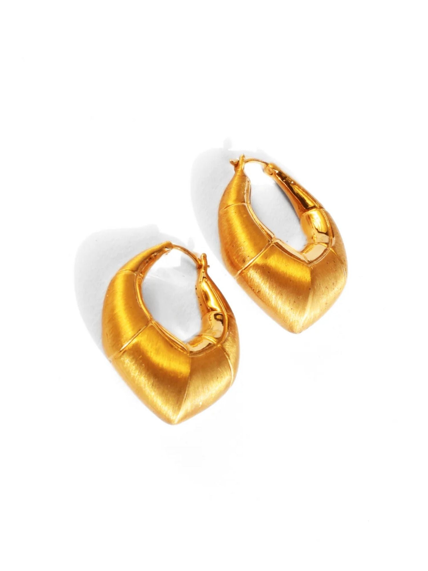 Flat lay of large gold claw hoop earrings showing brushed surface detail