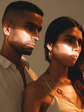 Model wearing small gold claw earrings in couple portrait, outdoor warm light