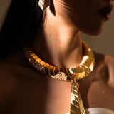 Model wearing green onyx earrings with matching gold collar necklace in dramatic lighting