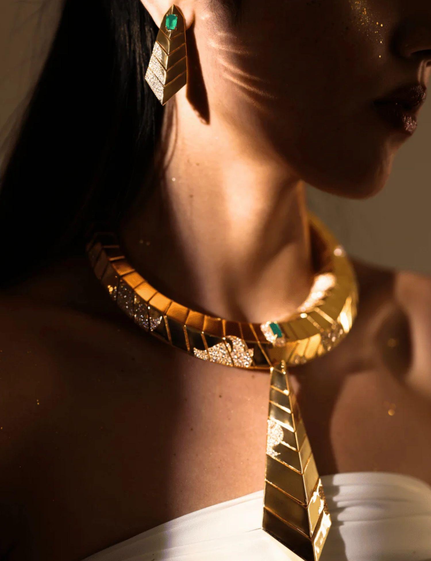 Model wearing green onyx earrings with matching gold collar necklace in dramatic lighting