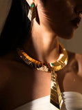 Model wearing green onyx earrings with matching gold collar necklace in dramatic lighting