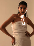 Full-body model shot in white dress wearing gold collar necklace with tie pendant