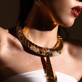 Model wearing gold collar necklace with matching green onyx earrings in warm light