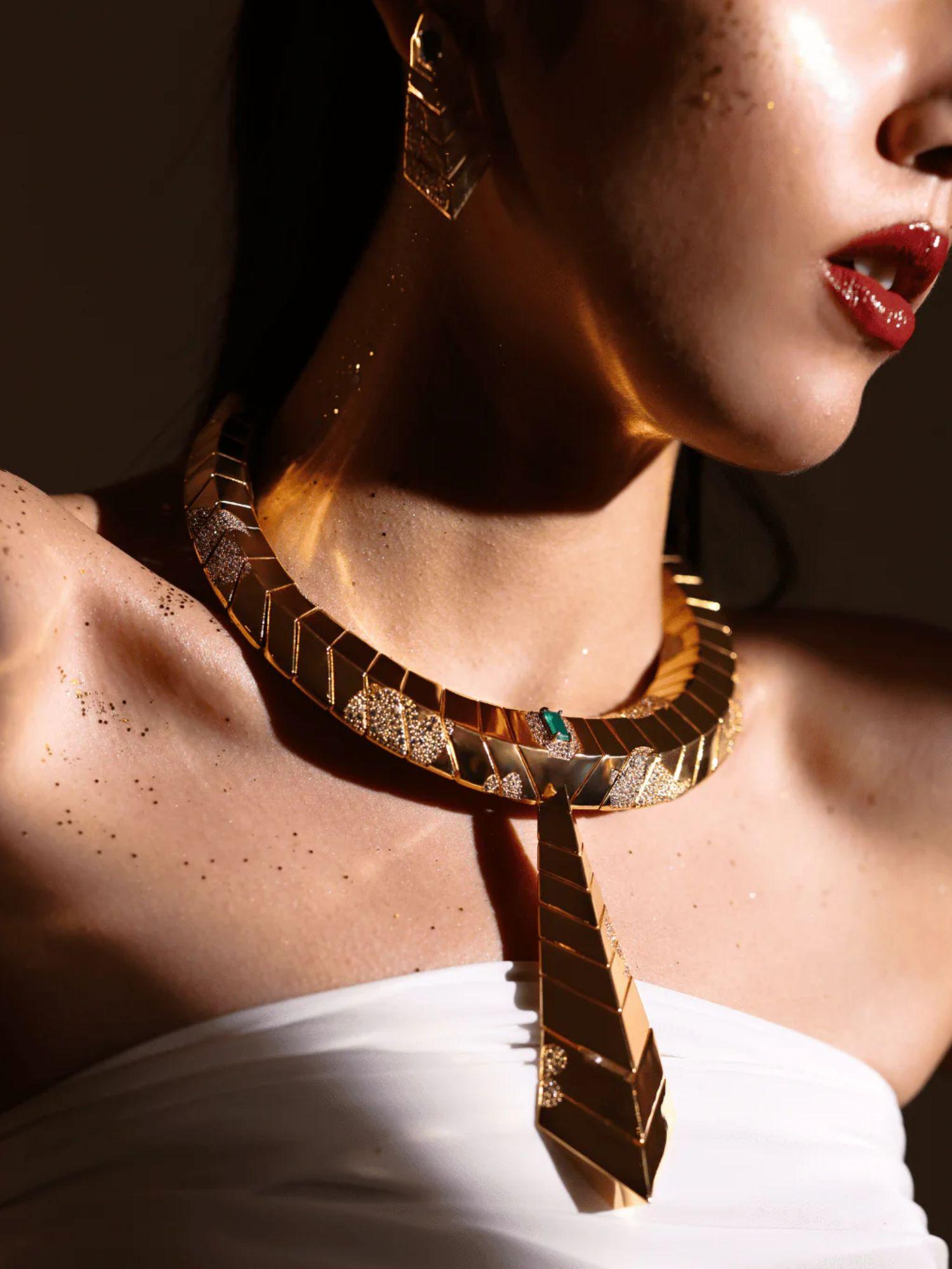 Model wearing gold collar necklace with matching green onyx earrings in warm light