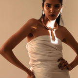 Model in white dress wearing sculptural gold collar necklace with tie pendant