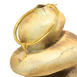 Close-up of gold choker bangle clasp mechanism on stone-textured prop