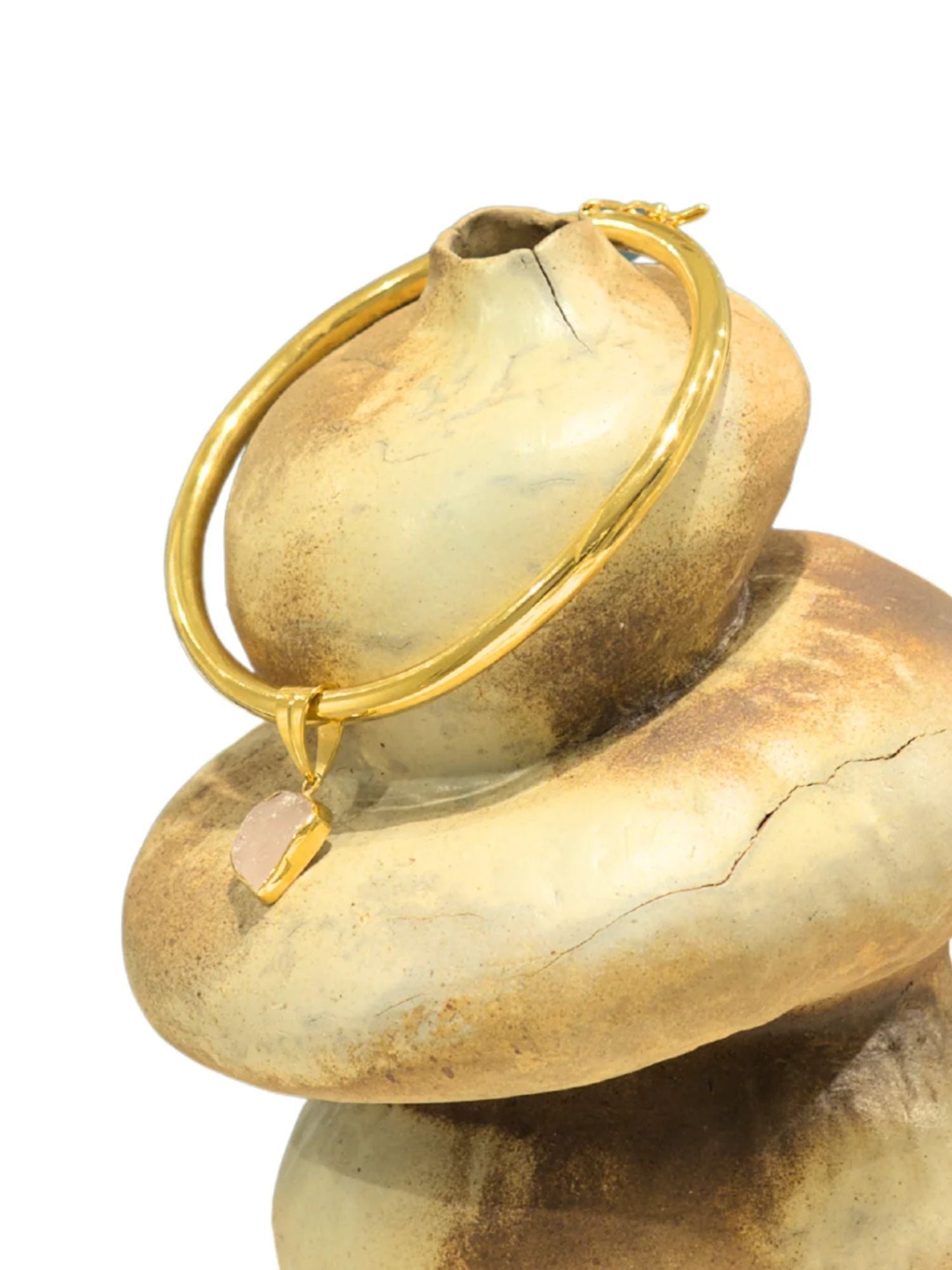 Close-up of gold choker bangle clasp mechanism on stone-textured prop