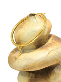 Close-up of gold choker bangle clasp mechanism on stone-textured prop