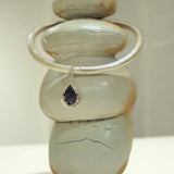 Silver bangle choker with black agate teardrop charm on stacked stone prop