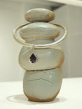 Silver bangle choker with black agate teardrop charm on stacked stone prop