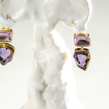 Close-up of gold amethyst and raw stone drop earrings on white prop