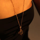 Model wearing raw citrine gold pendant necklace, black top collarbone shot