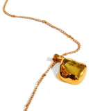Raw citrine pendant on fine gold chain on white background