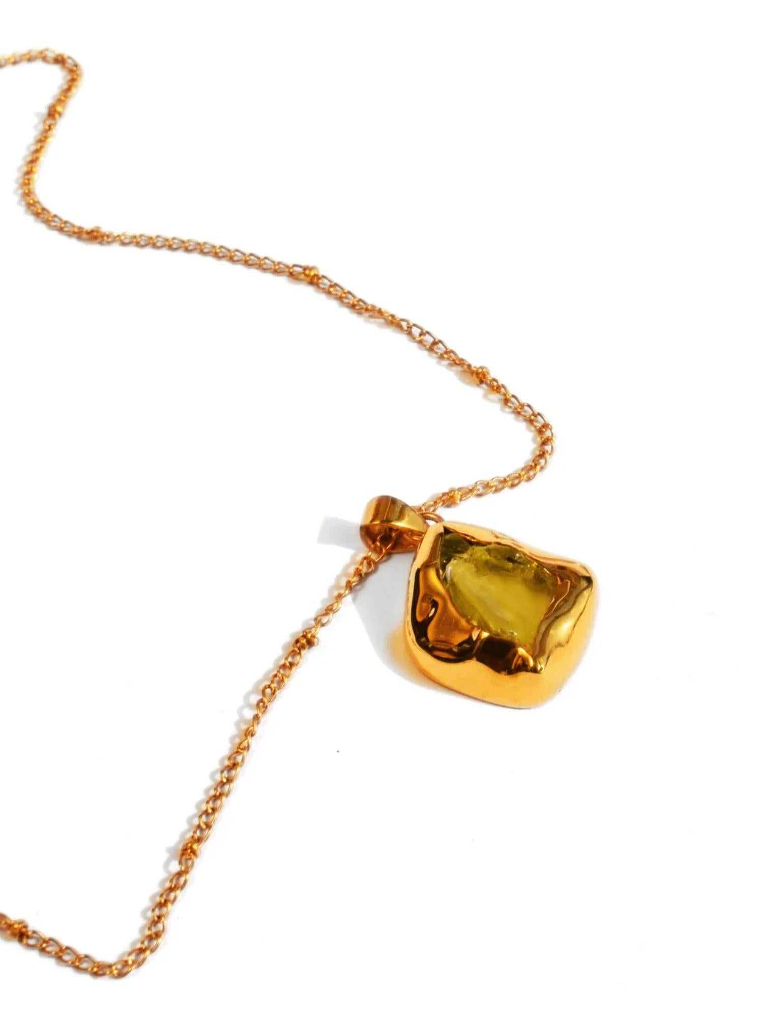 Raw citrine pendant on fine gold chain on white background