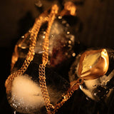 Raw stone gold pendant necklace draped over ice in dark editorial lighting