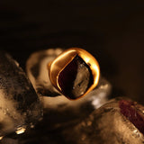 Gold raw agate cocktail ring held over ice, dramatic dark editorial shot