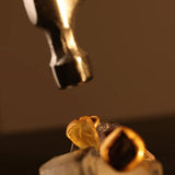 Gold raw citrine ring next to jewellery-making tool, detail process shot