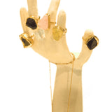 Multiple raw crystal rings in gold displayed on white hand-form prop