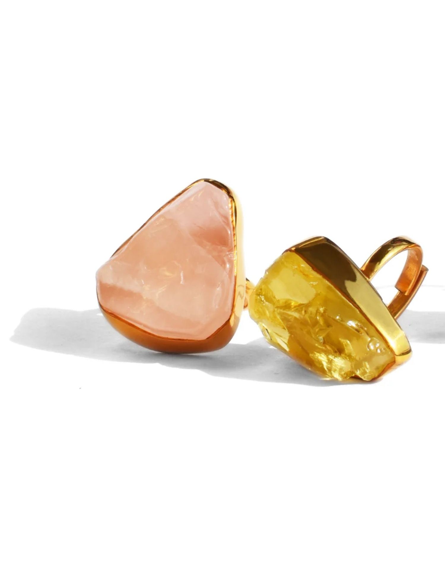 Rose quartz and citrine raw stone cocktail rings in gold setting on white