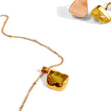 Gold pendant necklace with citrine stone and rose quartz earrings on white
