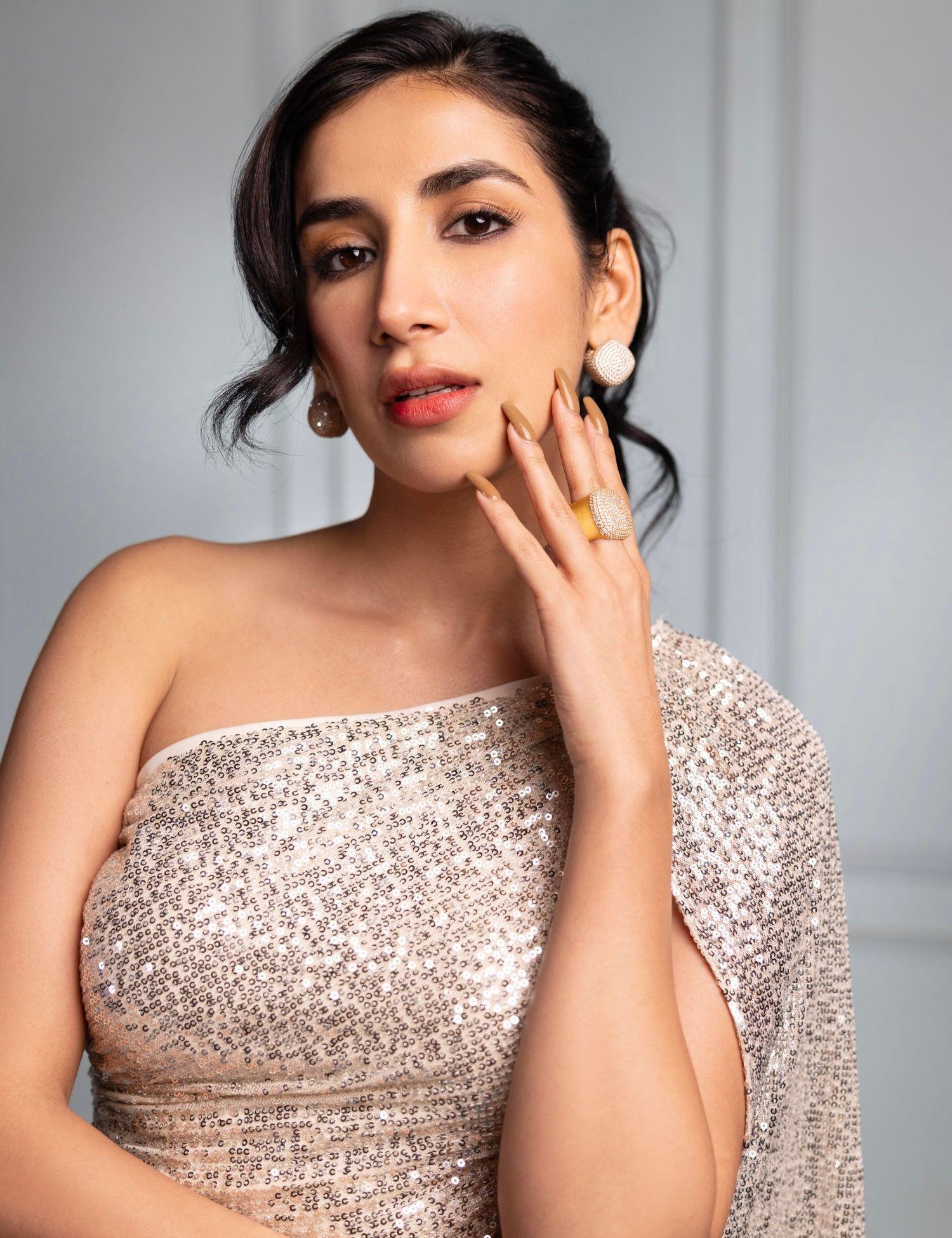 Model wearing gold cube earrings, hand near face in close portrait