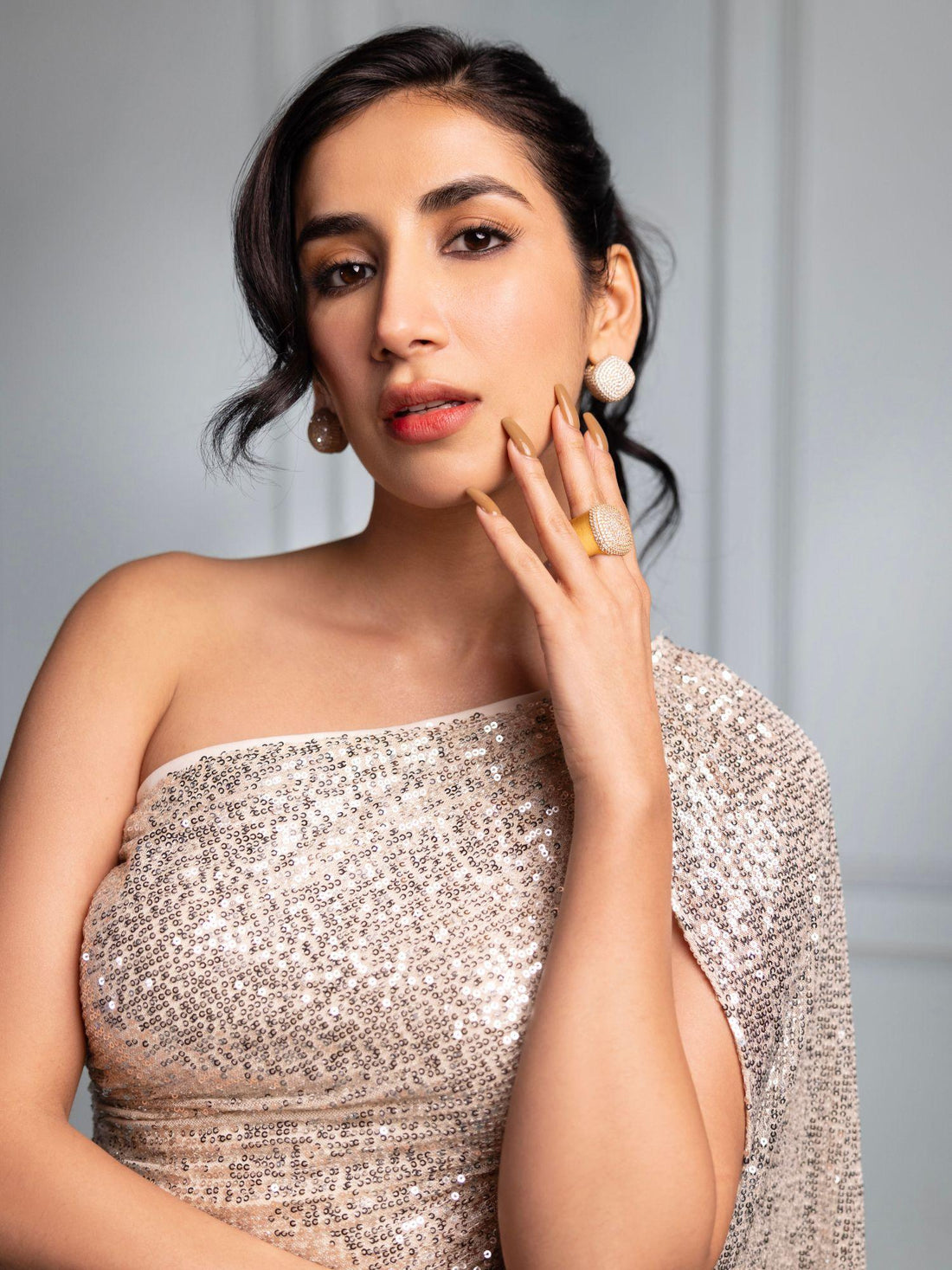 Model wearing gold cube earrings, hand near face in close portrait