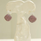 Ruby-pink CZ dome earrings displayed on white sculptural form, front view