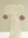 Ruby-pink CZ dome earrings displayed on white sculptural form, front view