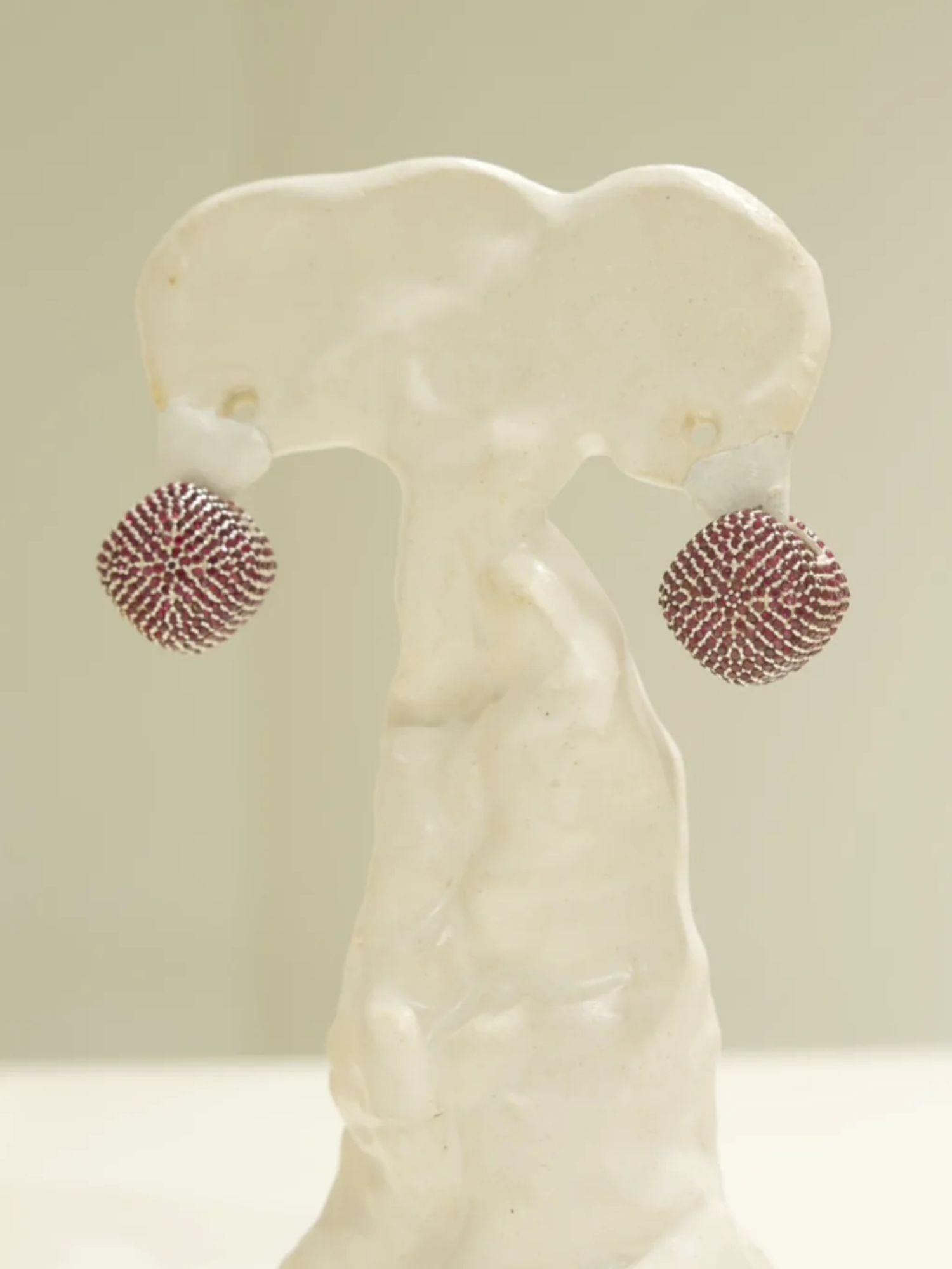 Ruby-pink CZ dome earrings displayed on white sculptural form, front view