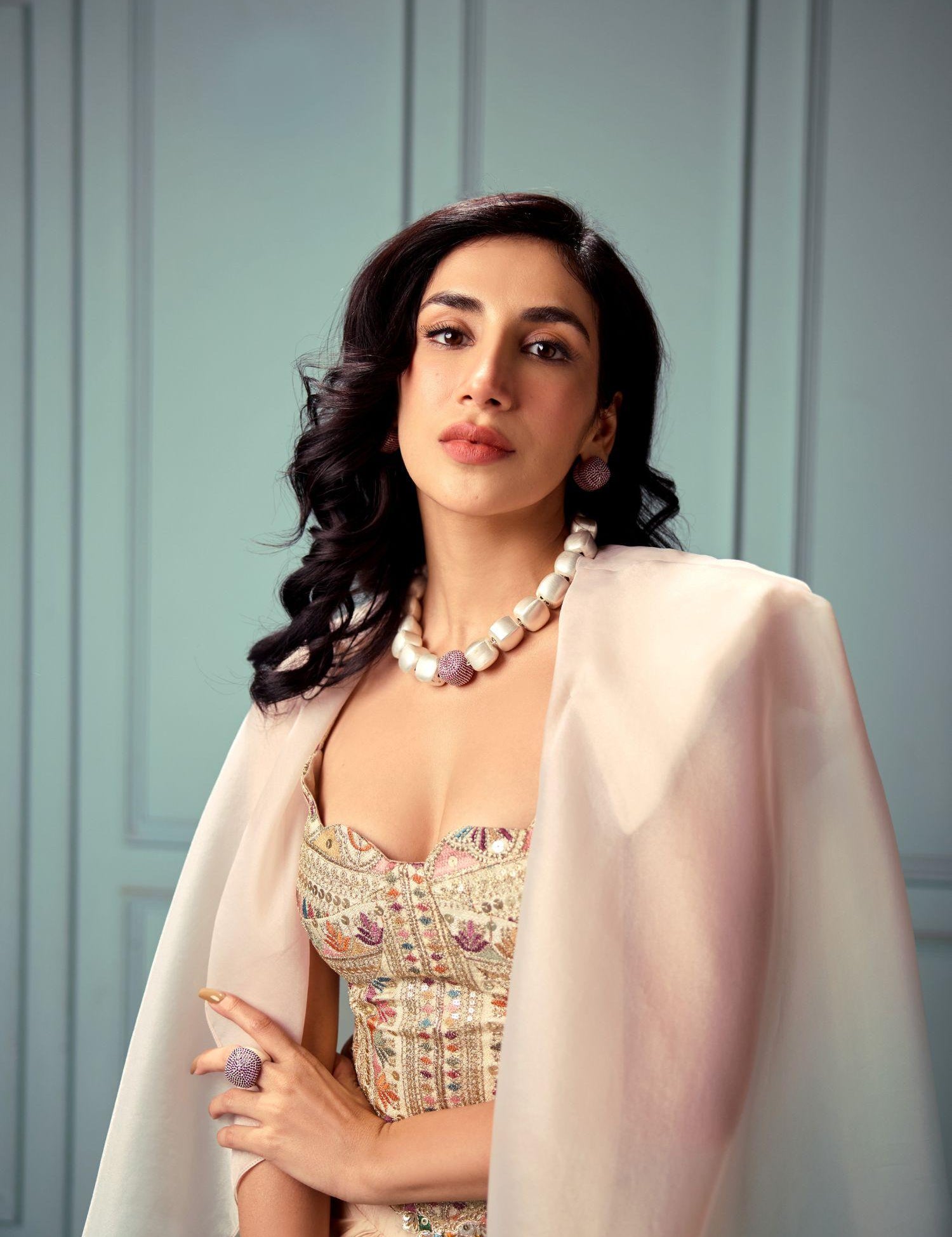 Model wearing brushed gold cube necklace styled with embroidered top
