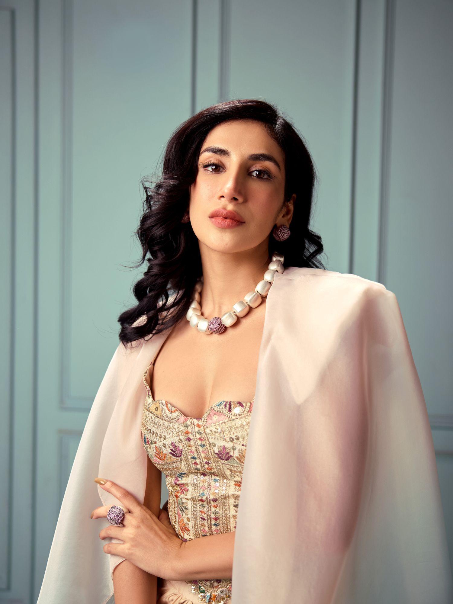 Model wearing brushed gold cube necklace styled with embroidered top
